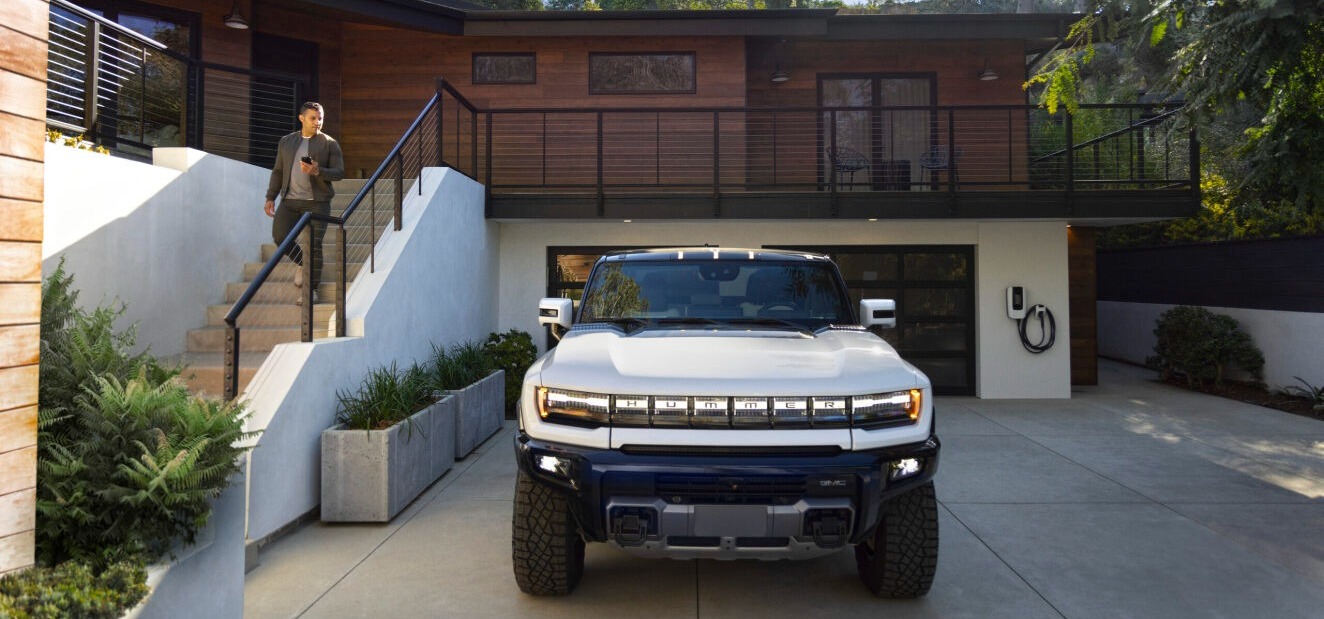 Unknown person walking down the stairs towards hummer EV that's parked on driveway